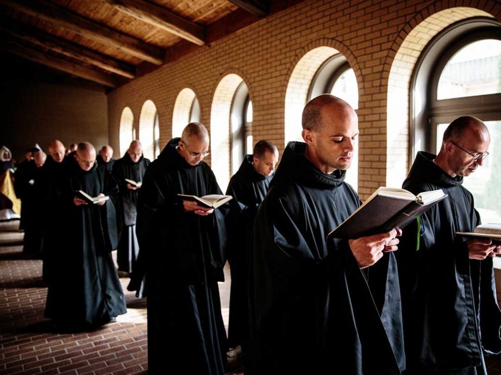 A two by two row of monks reading.