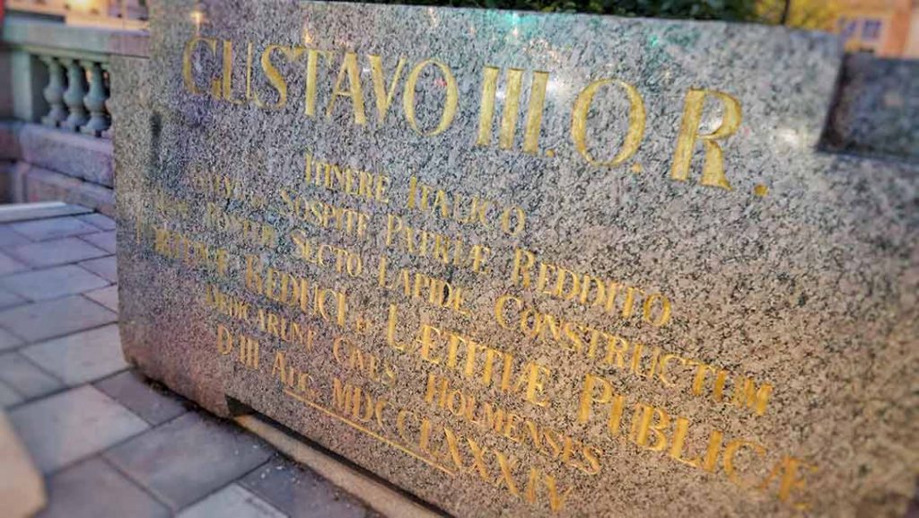 Golden inscription in Latin, about buildning a bridge in honour of Gustav III, on a pink granit slab.