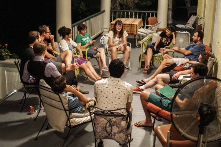 Group of Latin student in talking in a circle on a porch.