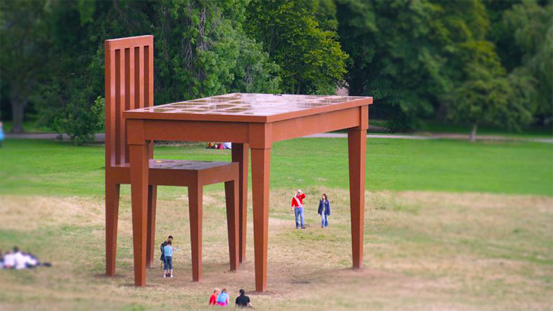 A sculpture of a giant table and chair, by Giancarlo Neri.